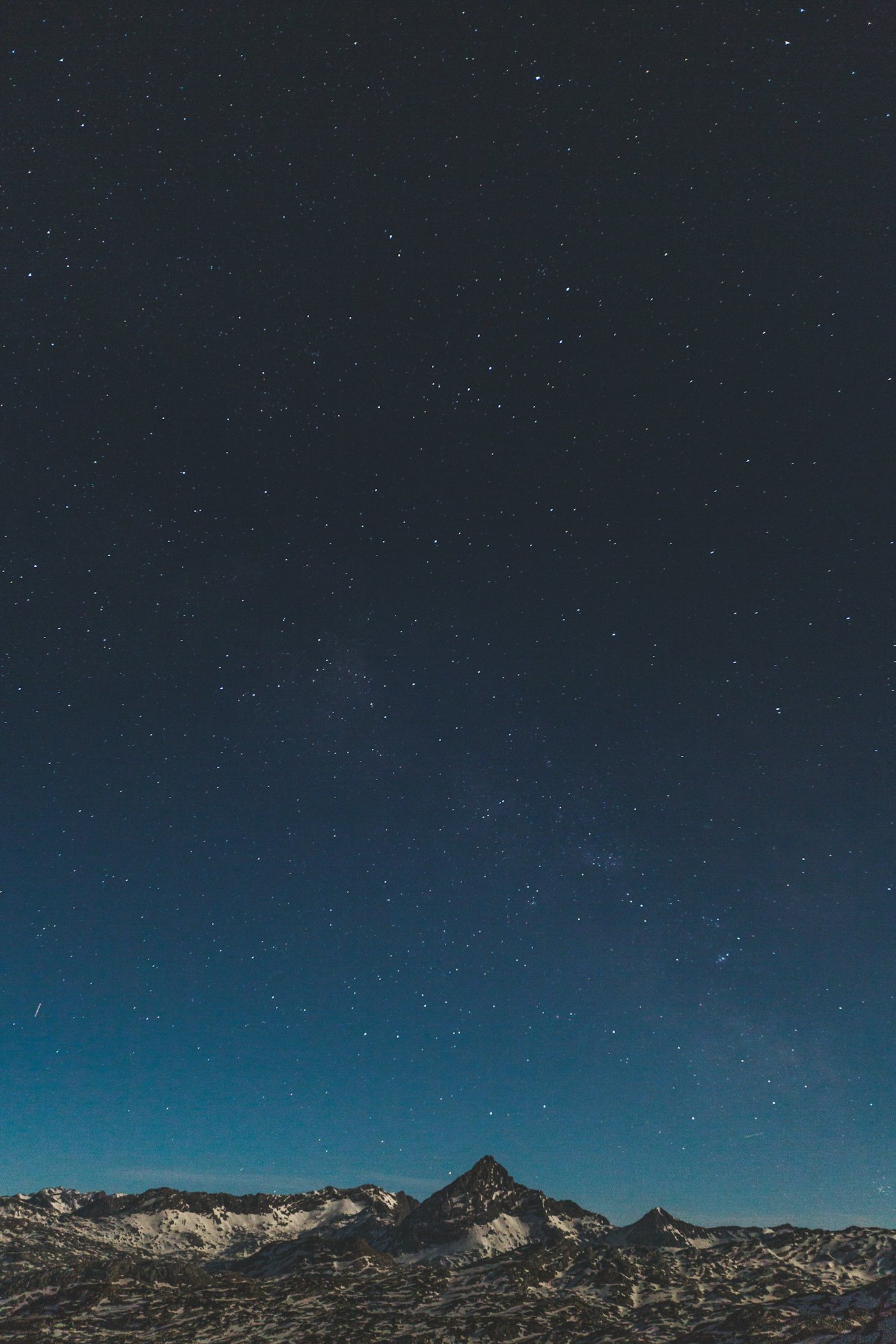 Pico nevado recortado contra un cielo nocturno lleno de estrellas
